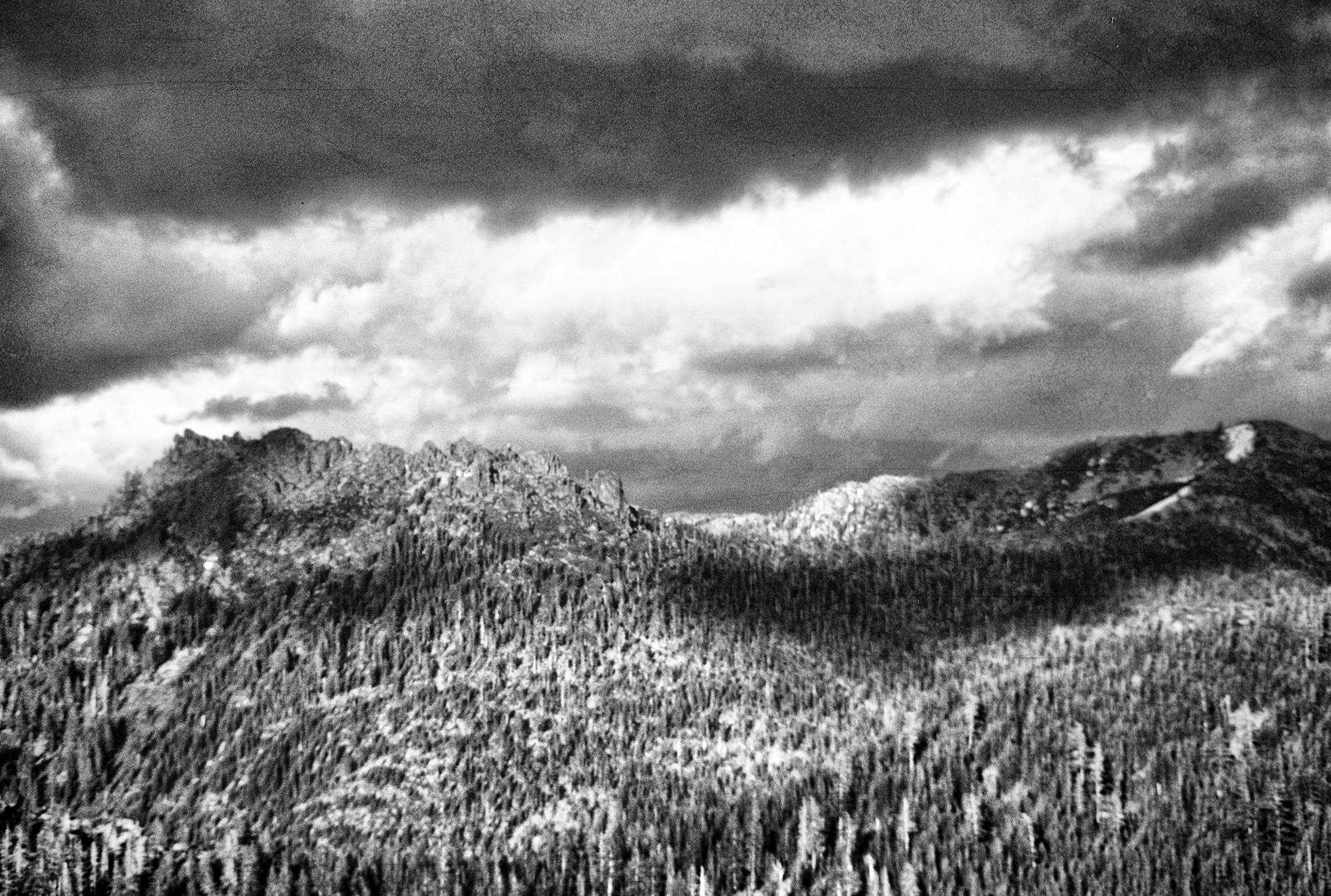 black and white photo of storm clouds coming over a butte.