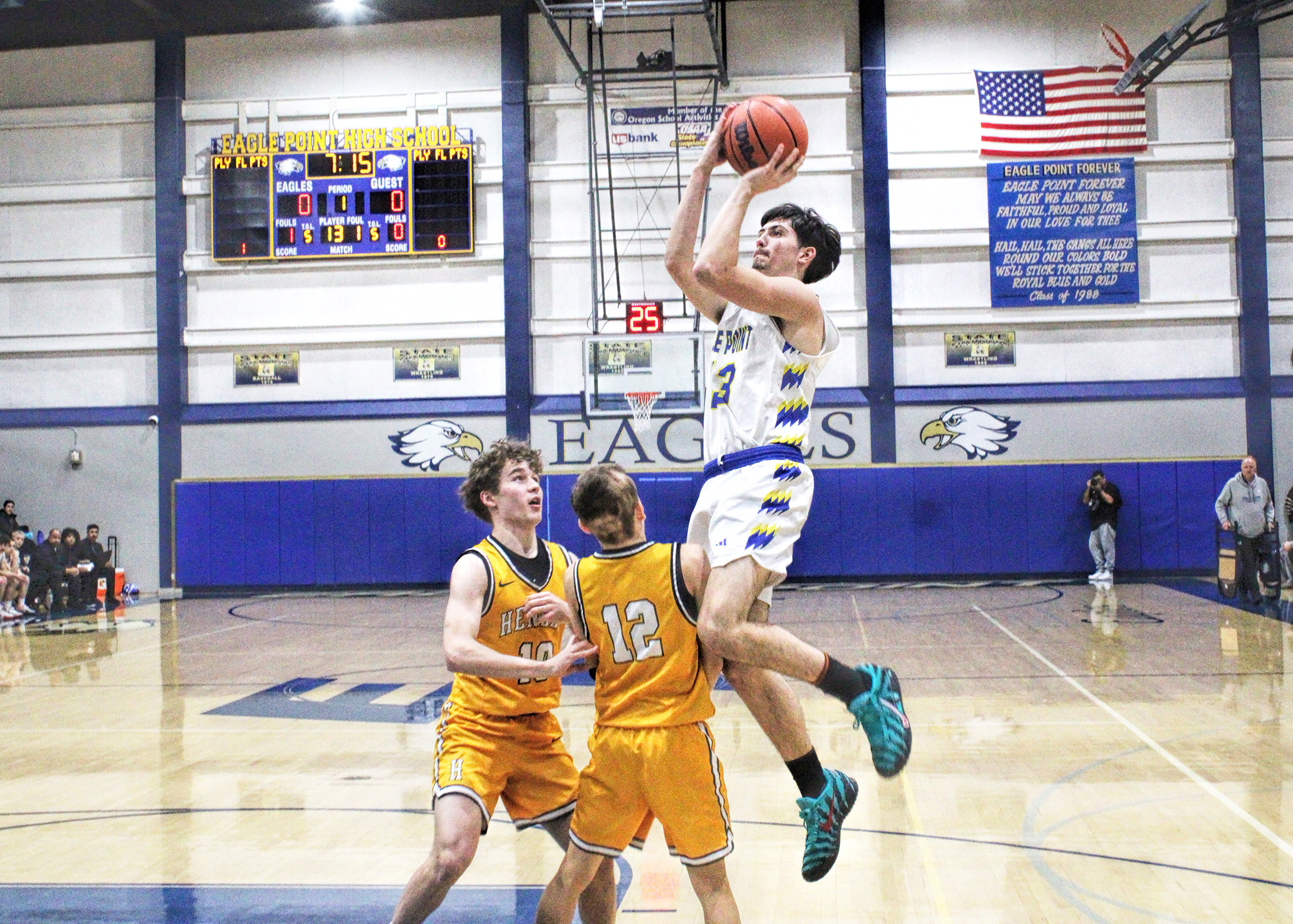 photo of an eagle point player jumping for a basket as two opposing players reach for him.