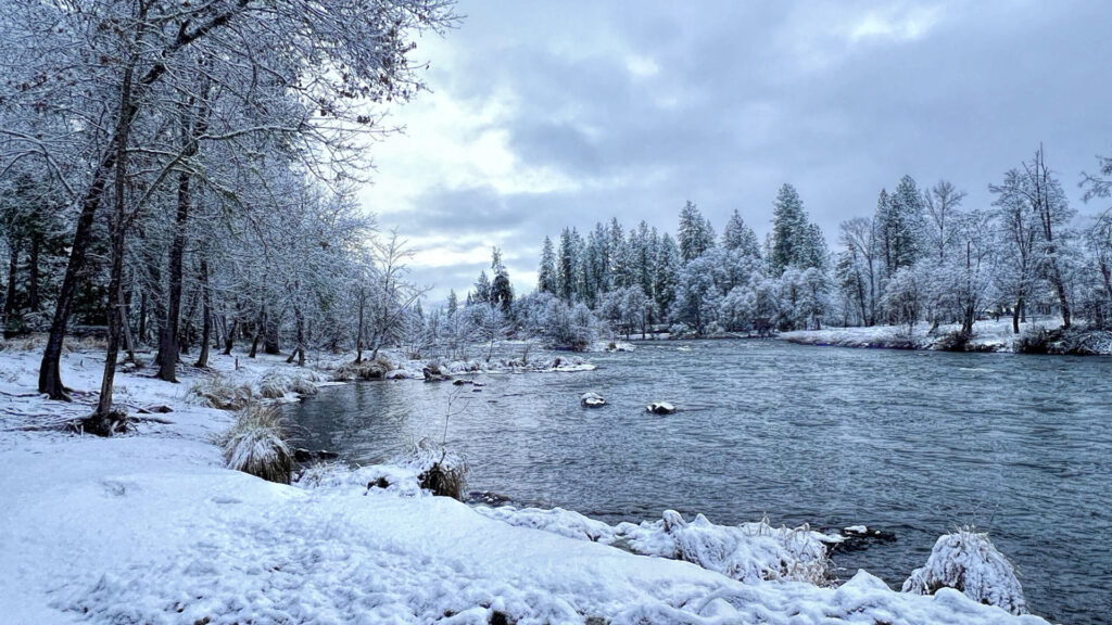 photo of a river with snowy banks and snow covered trees.