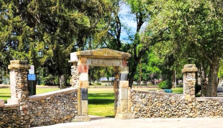 Photo of a rock wall split by a large arch with a carved center sign.