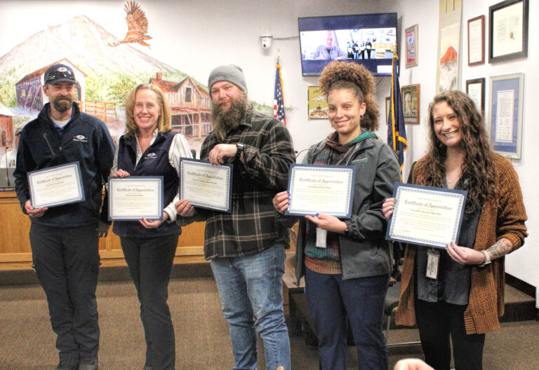 photo of five people standing and holding up award certificates.