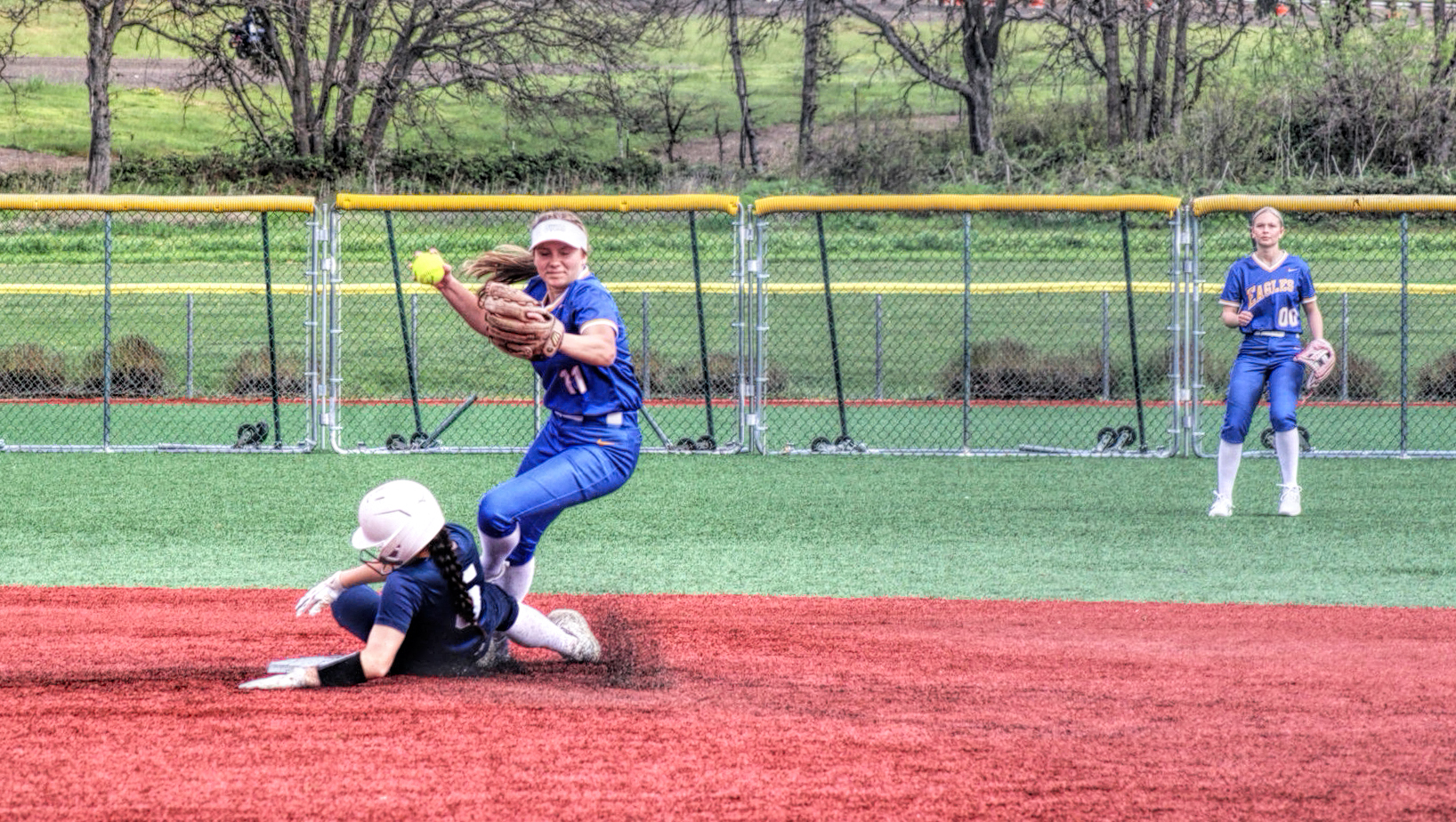 photo of a high school softball player who has just tagged out a runner and is about to throw the ball.