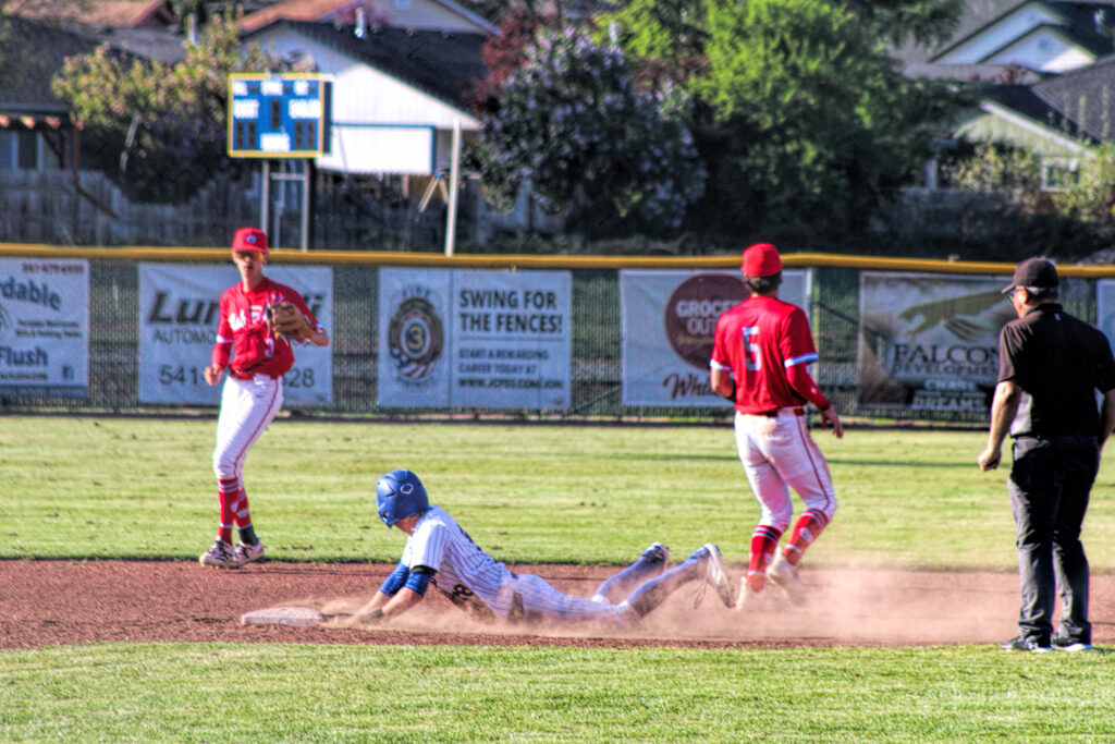 photo of a high school baseball game - a player is sliding head first into a base.