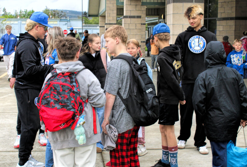 photo of two members of a high school baseball team talking with elementary school students.