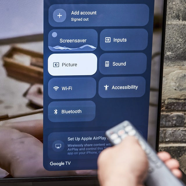 screen grab of someone holding up a remote and a TV setup screen showing on a TV.