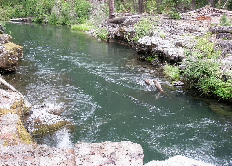 Photo of a river running with lava rock on either side.
