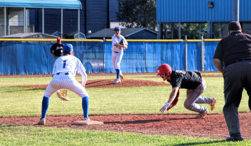 photo of a high school baseball game a runner is just starting their dive to slide into a base.
