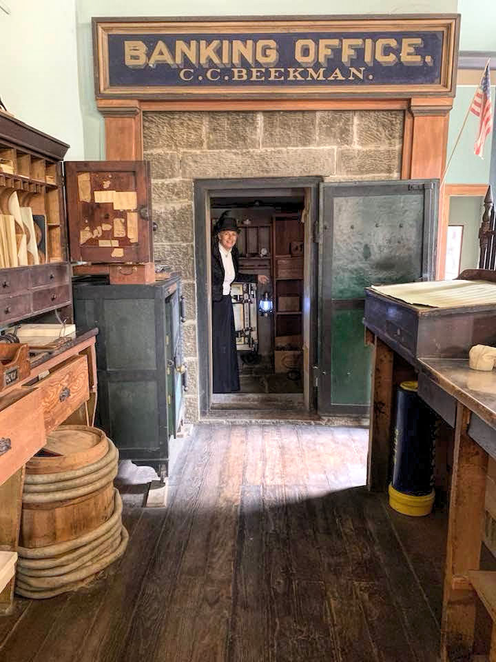 photo of an 1800s banking office with a woman in period clothing looking out of the doorway.