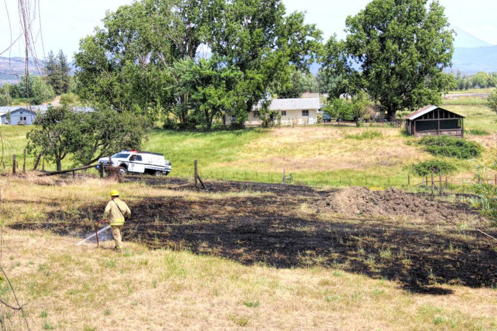 photo of a firefighter putting out the last bits of a grass fire.