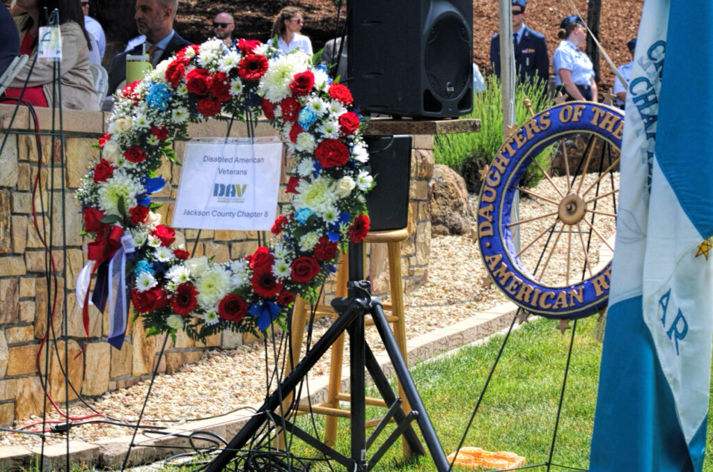 photo of a memorial wreath from the Disabled American Veterans and a round symbol and flag for the Daughters of the American Revolution.