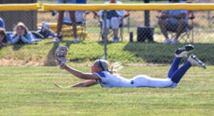photo of a high school softball fielder sliding to catch the ball.