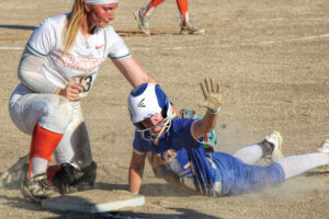 photo of a softball player holding up her hand after sliding into a base in a high school softball game.