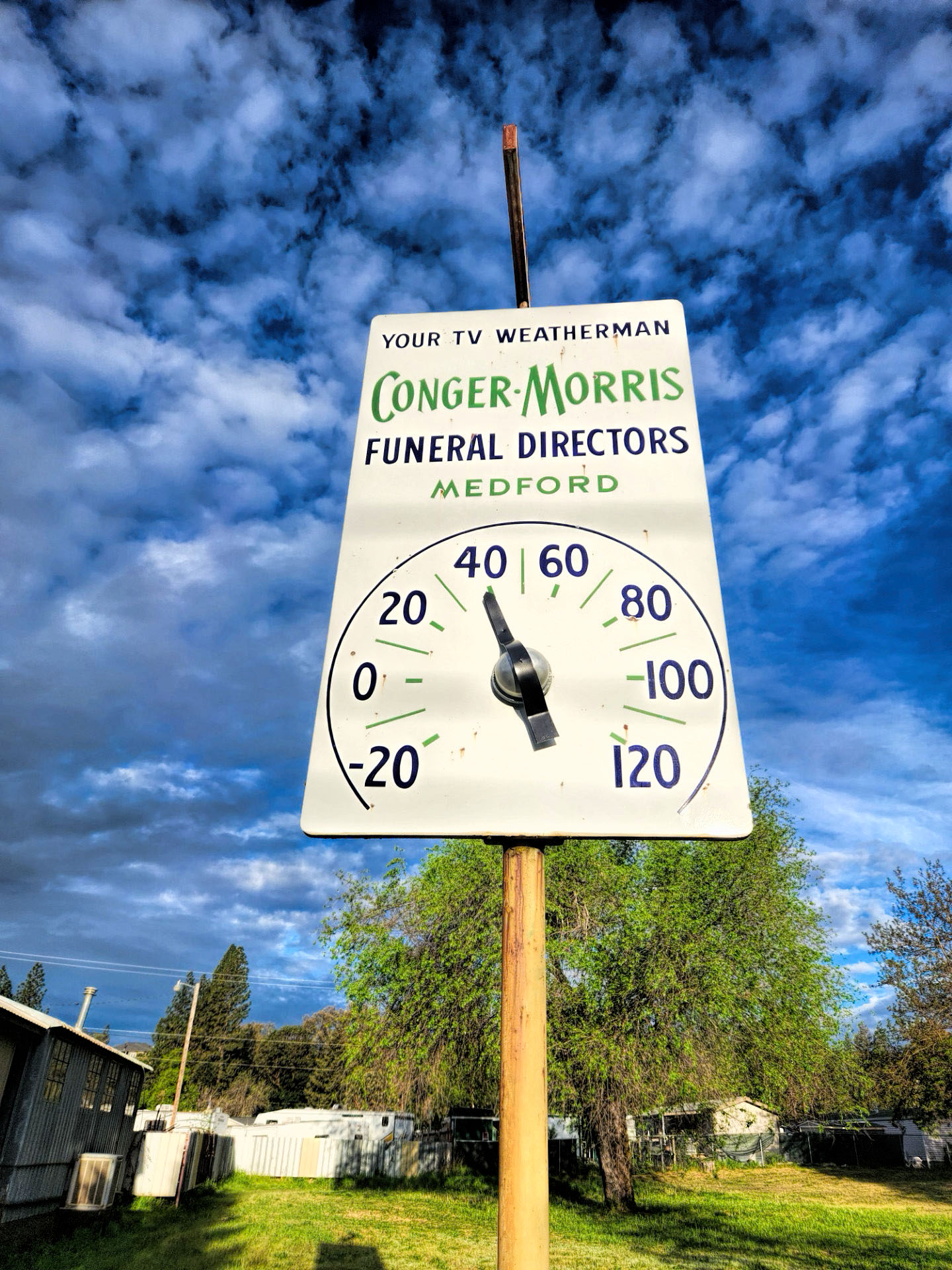 Photo of a large sign reading "Your TV Weatherman Conger-Morris Funeral Directors Medford" below the lettering is a working thermometer.