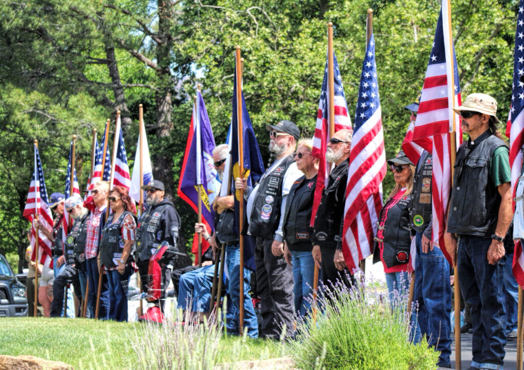 photo of a line of 15 veterans standing ad holding american flags and service flags.