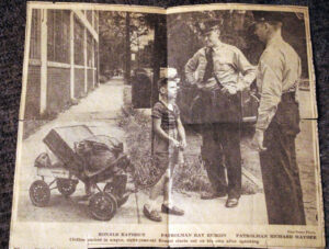 photo of an old newspaper clipping photo showing a young boy with belongings in a wagon looking up at one of two police officers talking to him.