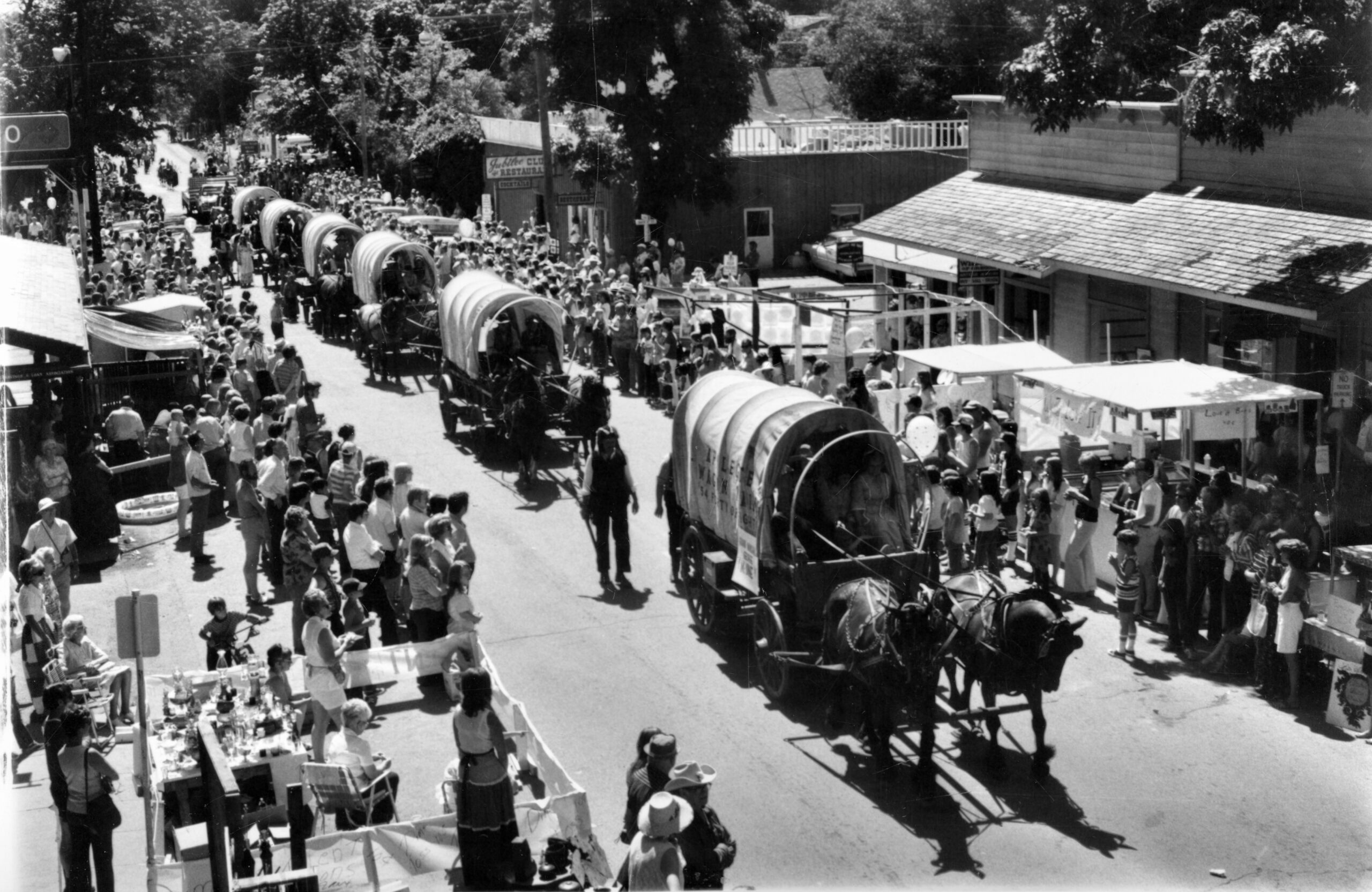 black and white photos of a parade of horse drawn covered wagons. It appears to be either the late 1970s or the early 1980s.