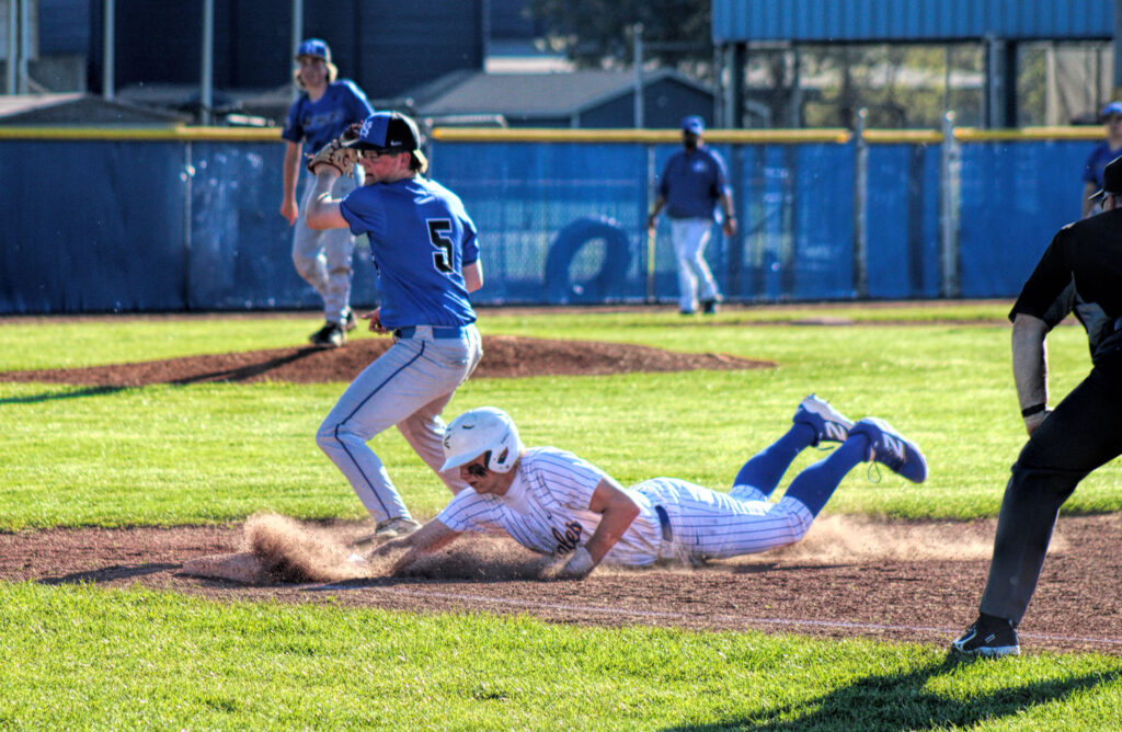 photo of a player sliding head first into a base in a high school baseball game.