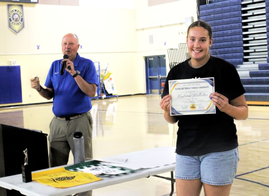 photo of a high school softball player holding up an award certificate.