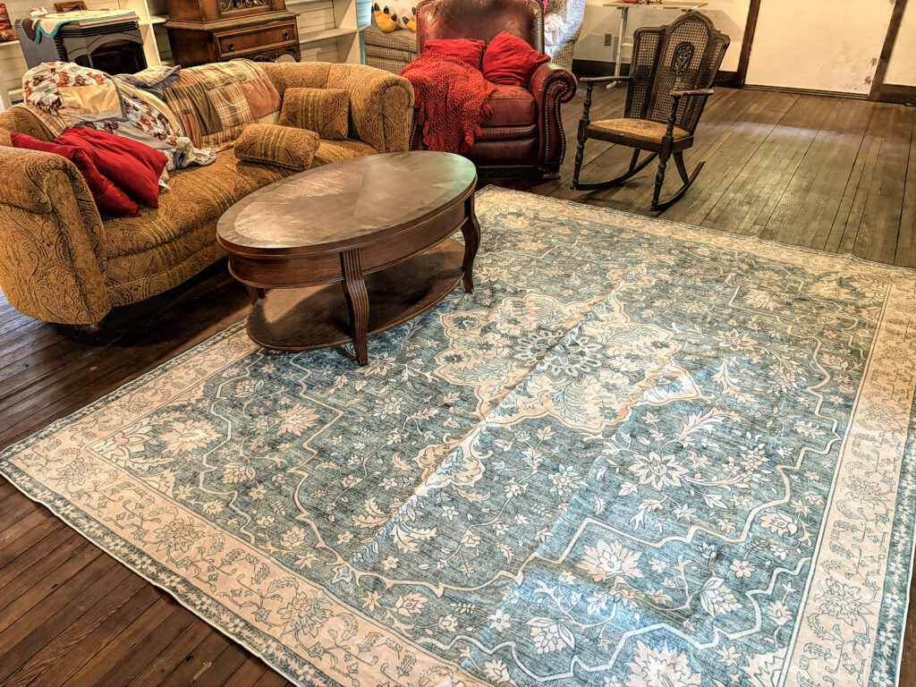 photo of a living room with a wooden floor ad a large area rug surrounded by furniture.