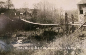 black and white photo of a footbridge over a creek.