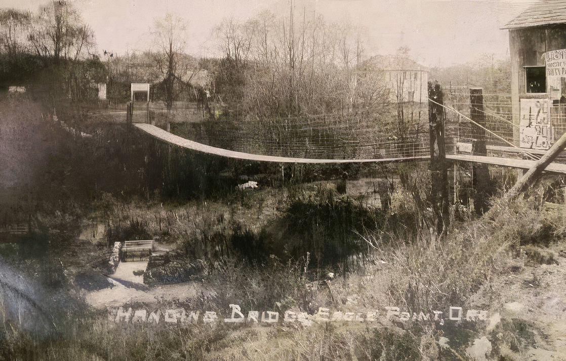 black and white photo of a footbridge over a creek.