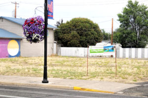 photo of a vacant lot with a "coming soon" sign for youth center expansion.