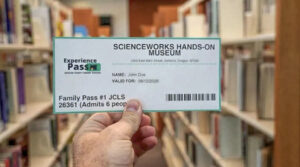 Photo of a hand holding a library experience pass.