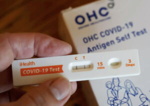 photo of a hand holding a positive covid test.