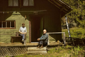 photo of a man and a woman sitting on the porch of a cabin.