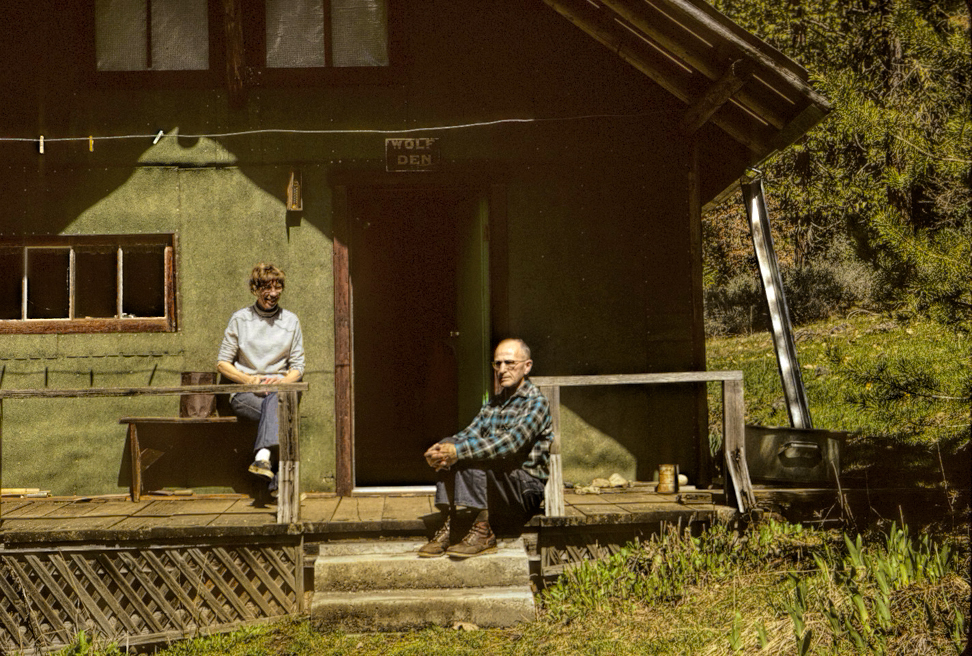 photo of a man and a woman sitting on the porch of a cabin.