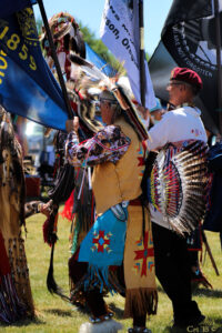 photo of Native American veteran honor guard in regalia holding various flags.