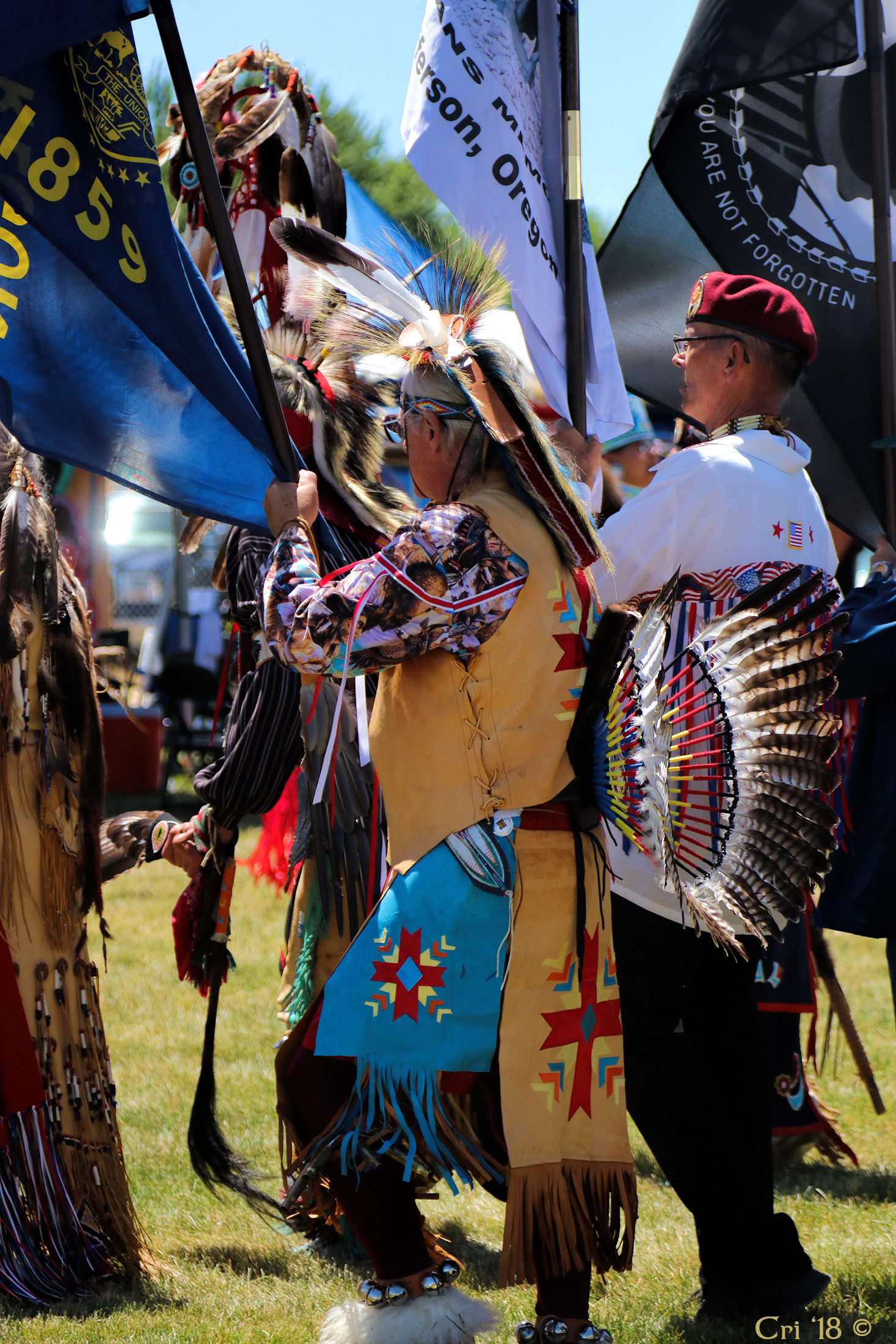 photo of Native American veteran honor guard in regalia holding various flags.