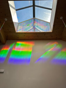 photo of a prism/rainbow art display - the prism is in a skylight, the rainbow on a wall.