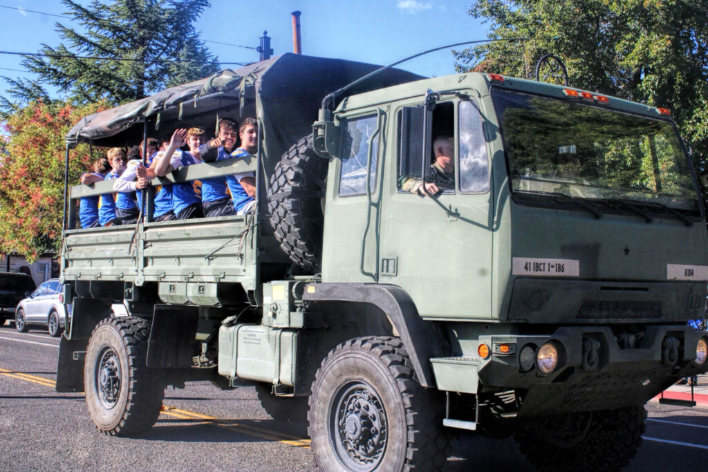 photo of high school football player riding in a military vehicle in parade.