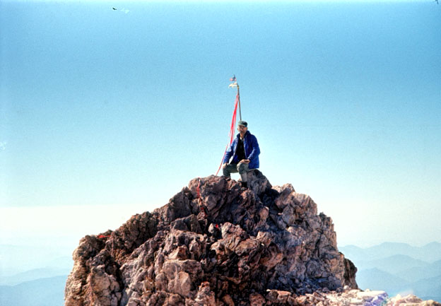 photo of a man sitting at the very top of Mt. Shasta.