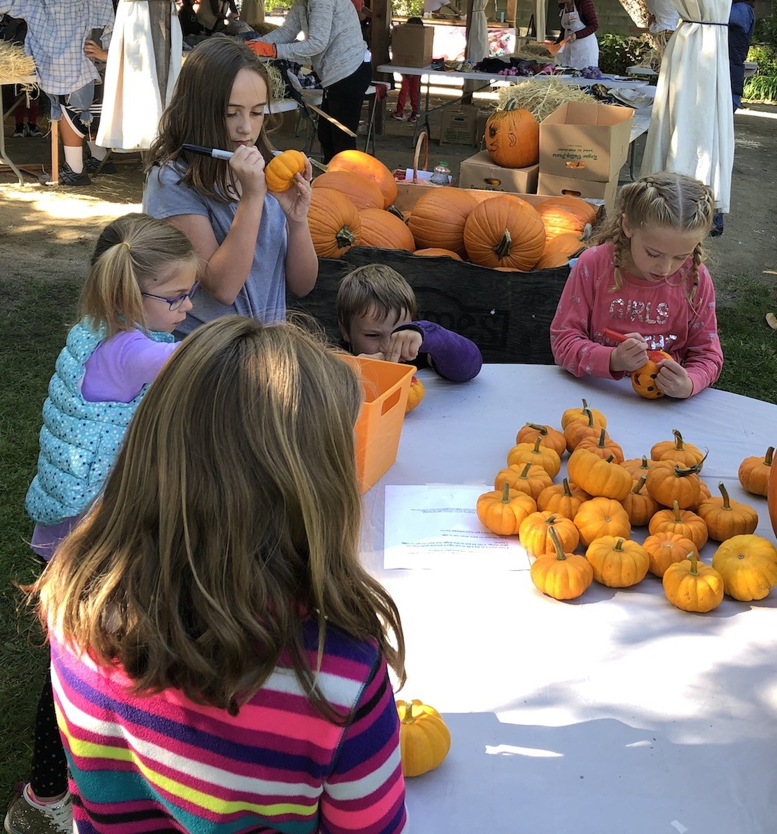 photo of children coloring faces on pumpkins.