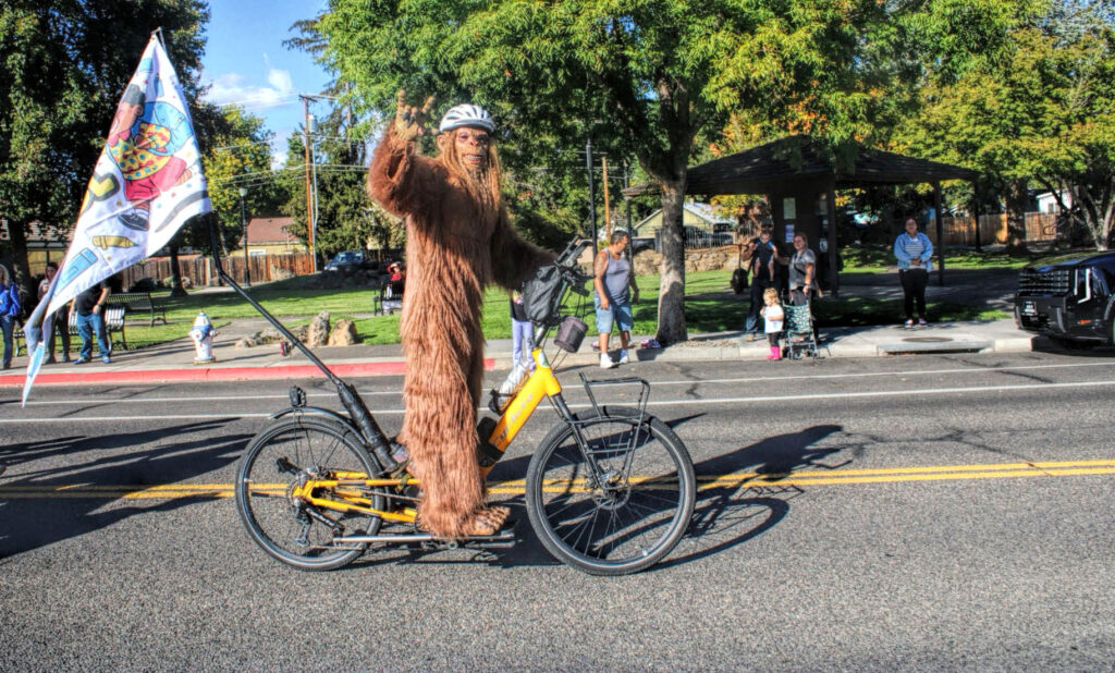 photo of sasquatch riding a stand up bike in a parade.