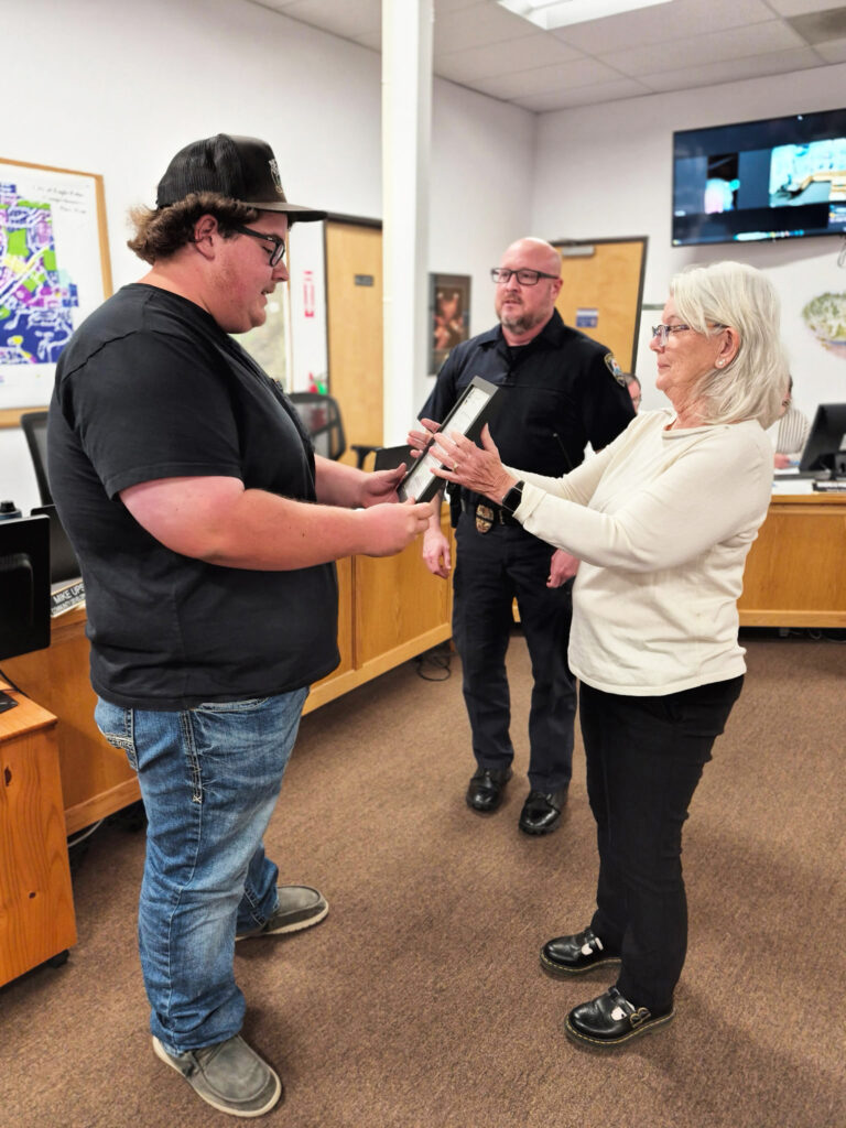 photo of a man being handed an award in a city meeting.