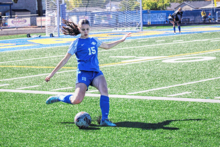 photo of a girl about to kick a soccer ball during a high school soccer game.