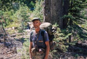 photo of a man in 1964 on a trail decked out in camping gear.