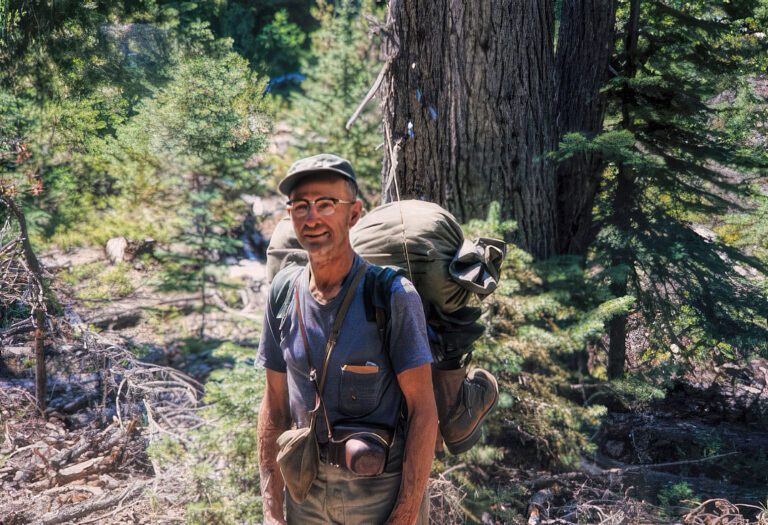 photo of a man in 1964 on a trail decked out in camping gear.