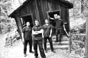 photo of four men standing in front of an abandoned building in a ghost town.