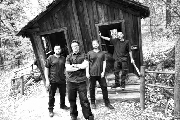 photo of four men standing in front of an abandoned building in a ghost town.